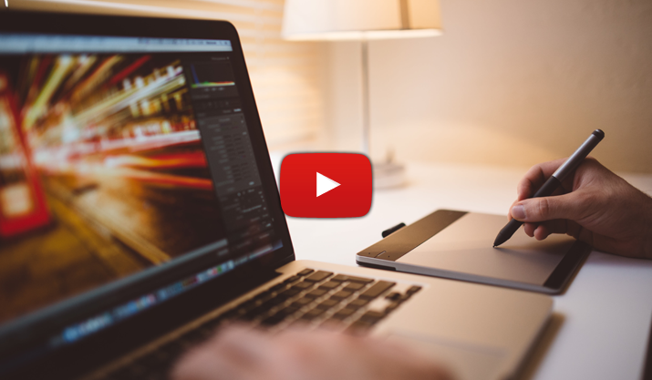 Hand zeichnet etwas mit elektronischem Stift, daneben ein aufgeklappter Laptop