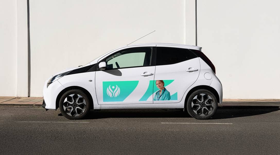 Ein Auto, auf dessen Türen eine Folie mit Unternehmenswerbung klebt.