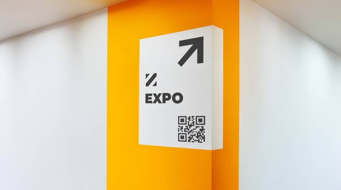 Eine weiße Wandecke, auf die eine gelbe Klebefolie zur Wegbeschreibung angebracht wurde.